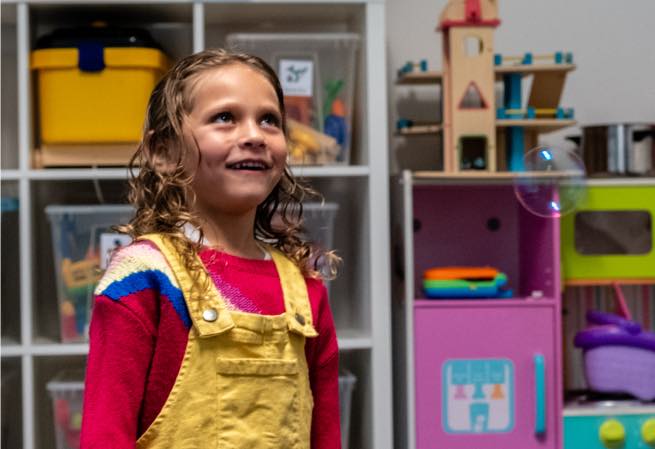 Young girl looking at bubbles during speech therapy at Voice Within Therapy Centre