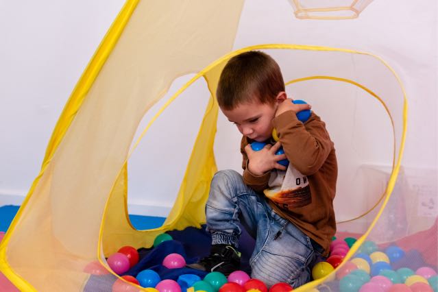 Young boy picking up balls in a ball pit at Voice Within Therapy Centre
