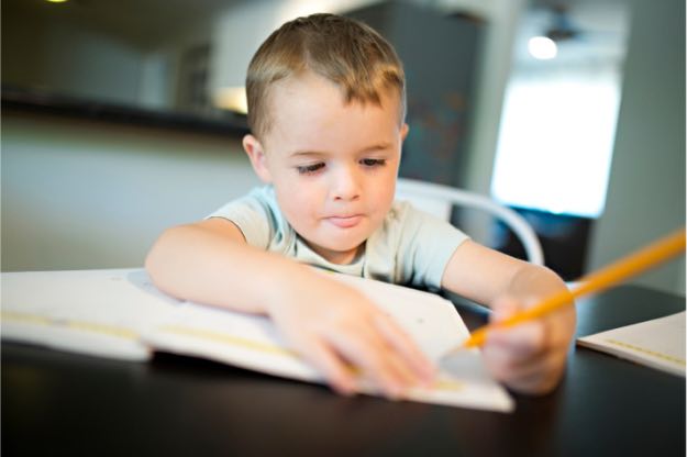School boy writing by himself