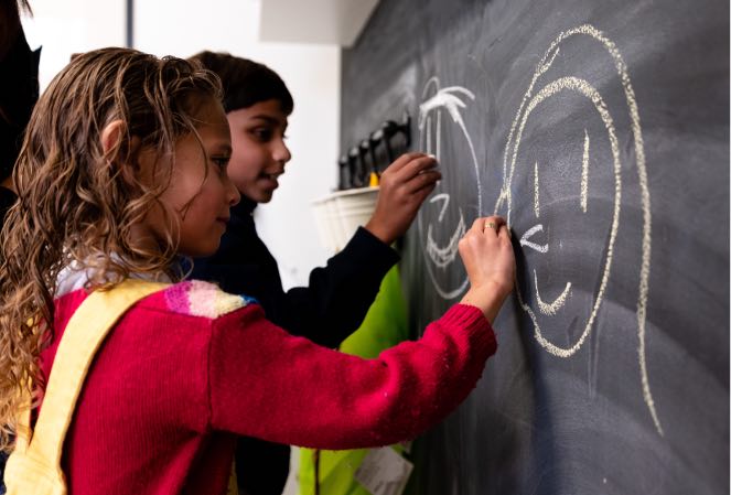 Young boy and girl drawing on chalkboard during Group Speech Therapy at Voice Within Therapy Centre